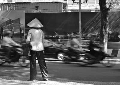 Ho Chi Minh Ville, mutations rapides, rêves de modernité, circulation dense. Sur le bord du trottoir, une femme hésite. Elle semble venir d’ailleurs, d’un monde ralenti, des campagnes vietnamiennes. Cliché : Pascal Clerc